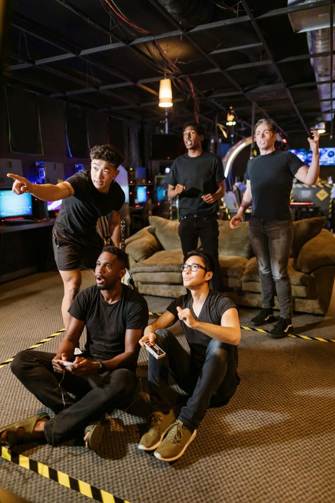 Five young adults gaming together in an arcade setting, enjoying teamwork and technology.